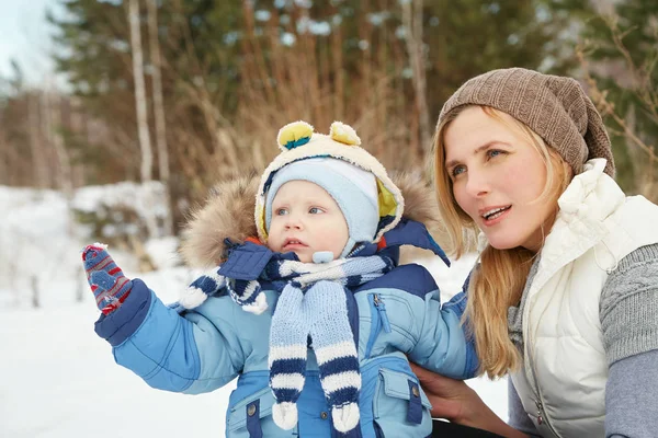 Glückliche Mutter und Baby im Winterpark. Familie im Freien. fröhliche Mama mit ihrem Kind. — Stockfoto