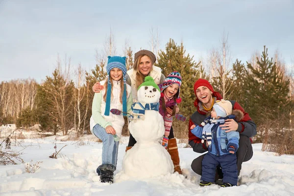 雪だるまと陽気な家族の肖像画。冬の屋外で幸せな親子. — ストック写真