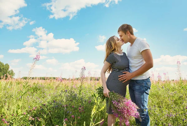 Junges glückliches Paar verliebt im Freien. Liebender Mann und schwangere Frau auf einem Feld. — Stockfoto