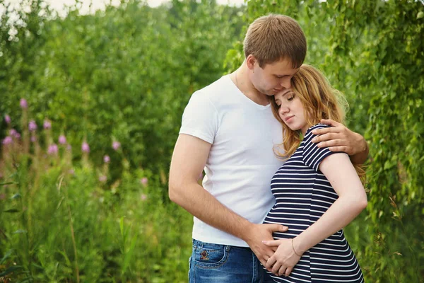 Joven pareja feliz enamorada al aire libre. hombre cariñoso y mujer embarazada en un parque . —  Fotos de Stock