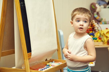 Küçük çocuk sehpaya resim yapıyor.