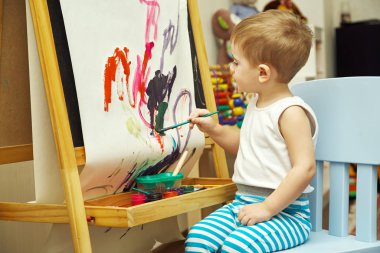 Küçük çocuk sehpaya resim yapıyor.