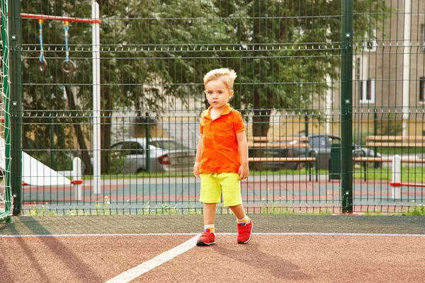 Divertente ragazzino al parco giochi con una griglia di cancello di calcio. giocare bambino sul campo sportivo . — Foto Stock