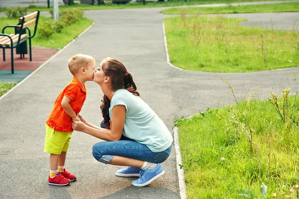 Anne ve oğlunu öpen açık hava portresi. Çocuk ve anne yürüyor.. — Stok fotoğraf