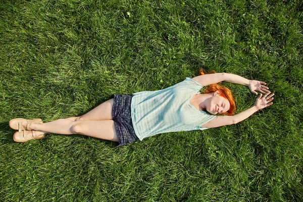 Relaxační zrzka dívka ležící na trávě. žena relaxační venkovní. — Stock fotografie