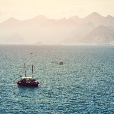 Dağların arkasındaki bir körfezde turist yelkenlisi..