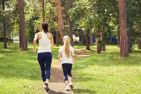 Sportieve moeder en dochter. vrouw en kind joggen in een park. outdoor sport en fitness familie. — Stockfoto