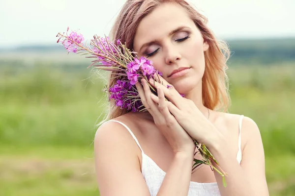 Außenporträt einer schönen blonden Frau mittleren Alters auf einem Feld mit Blumen. — Stockfoto