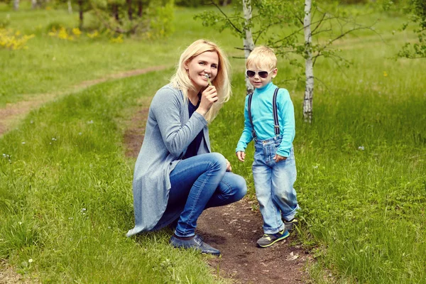 Figlio dare fiori a sua madre. bambino e mamma a piedi . — Foto Stock