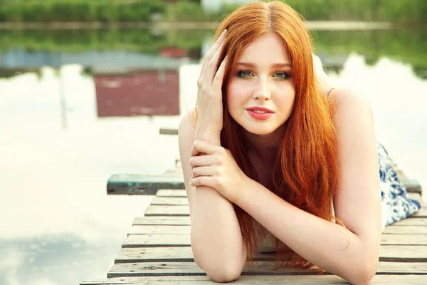 Retrato de verano de una joven pelirroja sobre el fondo del agua en el campo . — Foto de Stock