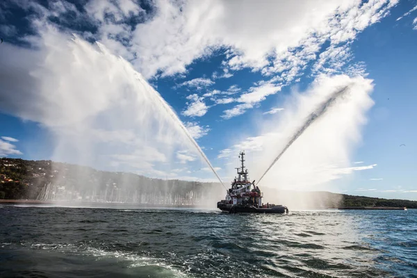 Tugboat shoots water at the World Offshore Sailing. — Stock Photo, Image