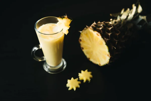 fruit drink. Glass of pineapple juice and slices of pineapple  on black background