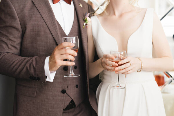 Hands of the bride and groom with glasses close up