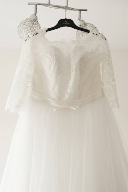 Gelinin gelinliği parlak bir odada bir avizeye asılı.