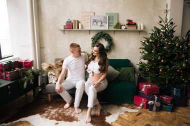 Genç bir koca ve hamile bir eş şık bir Noel arifesinde.