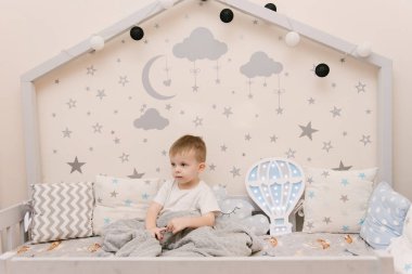 Çocuk odasında tahta bir odada oturan küçük tatlı bir oğlan.