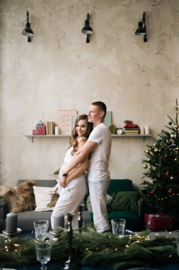 Genç bir koca ve hamile bir eş şık bir Noel arifesinde.