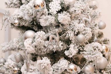 Gümüş oyuncaklar ve geyiklerle kaplı karla kaplı Noel ağacı.