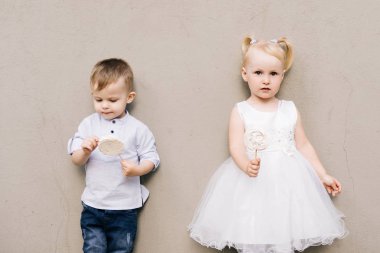 Tarz sahibi küçük bir çocuk ve kız gri bir arka planda ve şekerli Meri