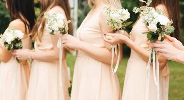 Güzel çiçekler taşıyan açık renk elbiseli muhteşem nedimeler.