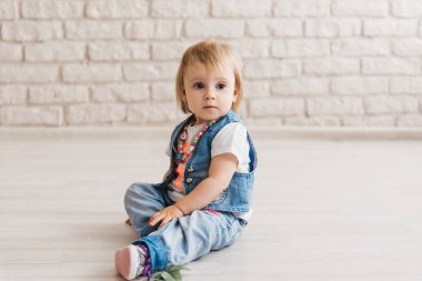 Yerde oturan gömlek ve kravatlı şirin çocuk.