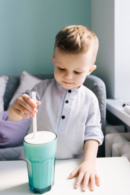 Çocuk kafesinde milkshake içen mutlu, şık bir erkek bebek.