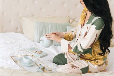 Hamile bir kızın güzel bir fotoğrafı. Kız yatakta kahvaltı yapıyor.