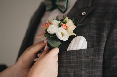 Gelin damat için yaka çiçeği giyiyor. Şık bir düğün.