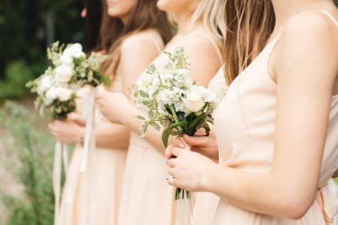 Güzel çiçekler taşıyan açık renk elbiseli muhteşem nedimeler.