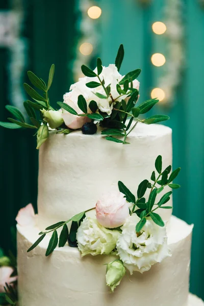 三层婚礼蛋糕，绿色靠背上有鲜花 — 图库照片