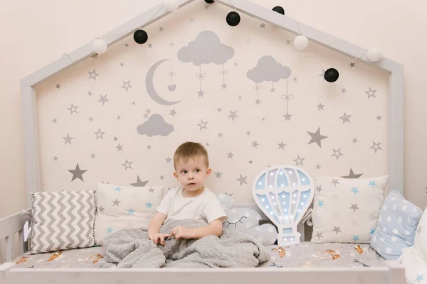 Pequeño niño lindo sentado en la habitación de los niños en un ser de madera — Foto de Stock