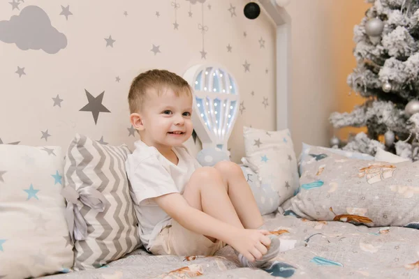 Kleiner süßer Junge sitzt im Kinderzimmer in einem hölzernen — Stockfoto