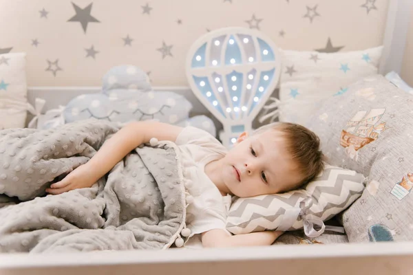 Маленький милый мальчик лежит в детской комнате в деревянной кровати h — стоковое фото