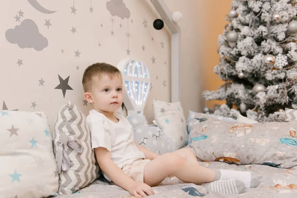 Kleiner süßer Junge sitzt im Kinderzimmer in einem hölzernen — Stockfoto