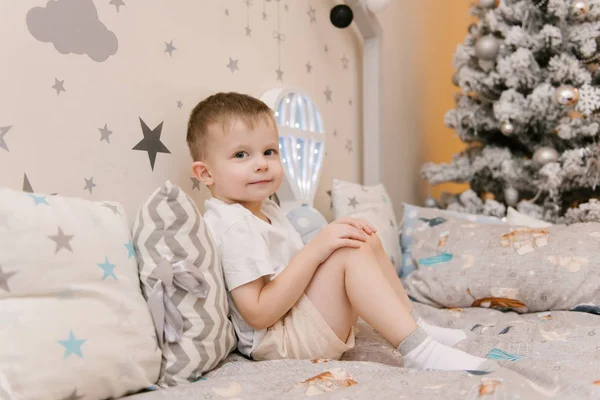 Kleiner süßer Junge sitzt im Kinderzimmer in einem hölzernen — Stockfoto