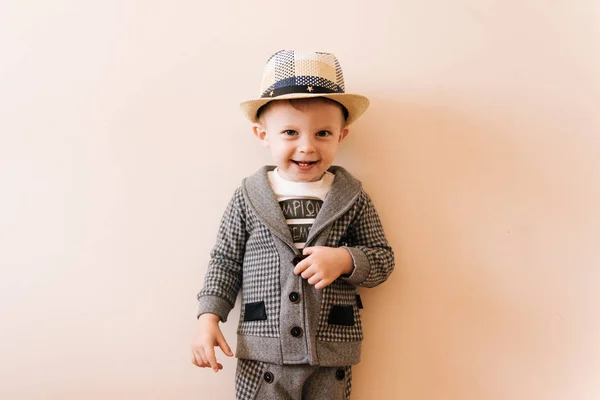 Szczęśliwy chłopiec w szarym garniturze, kapelusz na jasnym tle — Zdjęcie stockowe