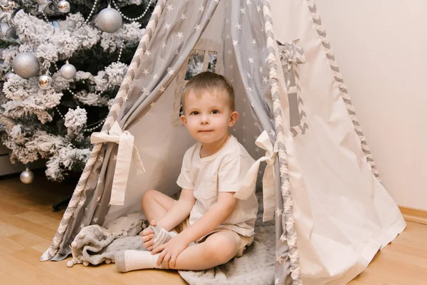 Een kleine schattige baby jongen zit in de kinderkamer in een tien — Stockfoto