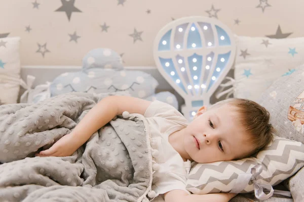 Pequeño bebé lindo se encuentra en la habitación de los niños en una cama de madera h — Foto de Stock