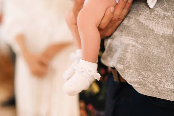 Pernas de uma criança pequena em meias brancas nas mãos de um pai homem — Fotografia de Stock