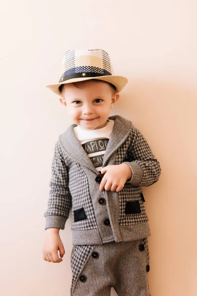 Lykkelig liten gutt i grå dress, hatt med lys bakgrunn – stockfoto