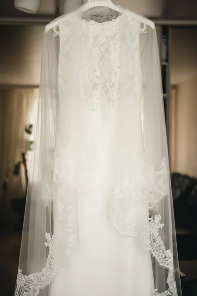 La robe de mariée de la mariée est suspendue à un lustre dans une pièce lumineuse — Photo