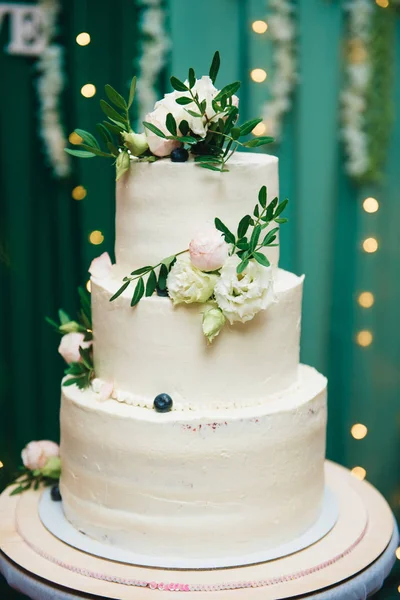 Pastel de boda de tres niveles con flores frescas en un fondo verde —  Fotos de Stock