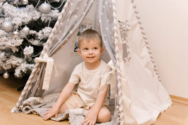 Een kleine schattige baby jongen zit in de kinderkamer in een tien — Stockfoto