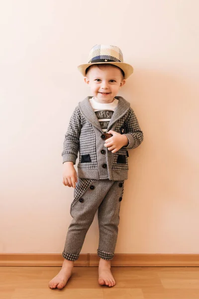 Szczęśliwy chłopiec w szarym garniturze, kapelusz na jasnym tle — Zdjęcie stockowe