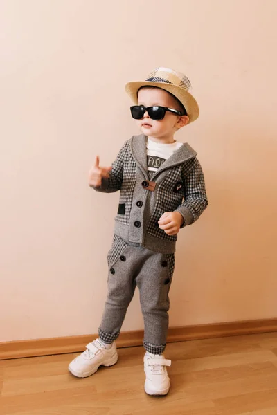 快乐的男婴，身穿灰色西装，戴着浅色背景的帽子和眼镜 — 图库照片