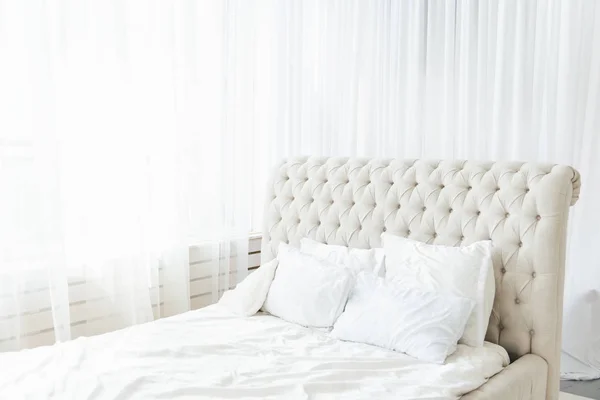 Белая спальня со светлой кроватью и высоким изголовьем, свет от — стоковое фото