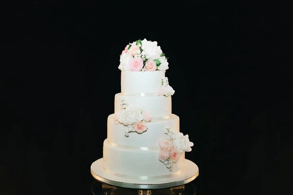 Luxo bolo branco de quatro camadas com flores no fundo preto, nós — Fotografia de Stock