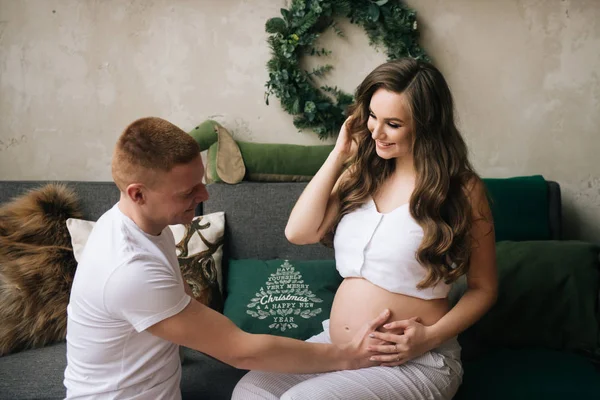Young husband listens to the heartbeat of the future baby pregnant wife