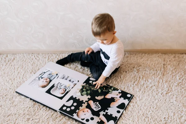 Şirin bir bebek oturuyor ve fotoğraflarıyla büyük bir fotoğraf kitabına bakıyor. Çocuk fotoğraf albümü