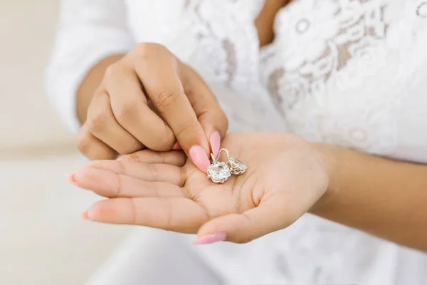 Kvinnors bröllop smycken (örhängen) i händerna på bruden, se — Stockfoto